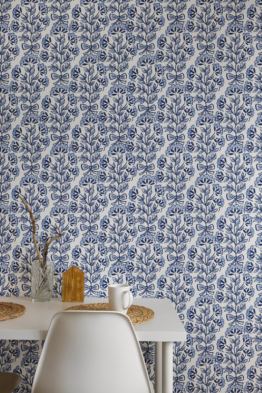 A table and chairs against a blue and white floral patterned wall.