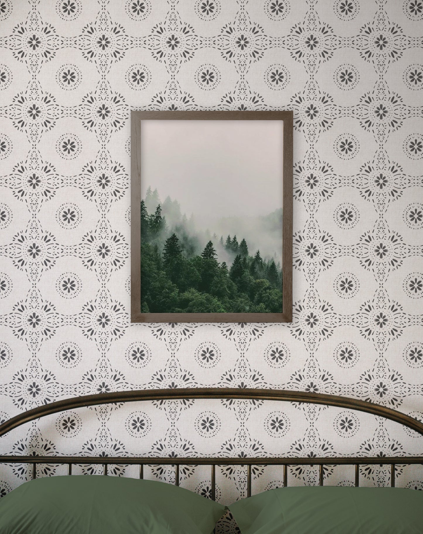 Framed print of a forest scene on a patterned wall above a bed.
