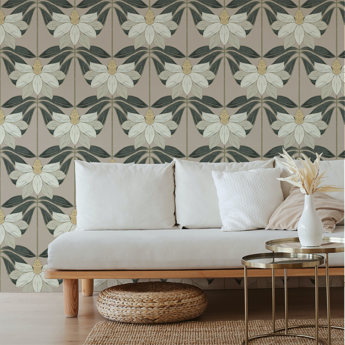A styled living room scene featuring a light beige sofa with white and beige pillows, set against a wall with a repeating floral wallpaper pattern in muted green, beige, and cream.