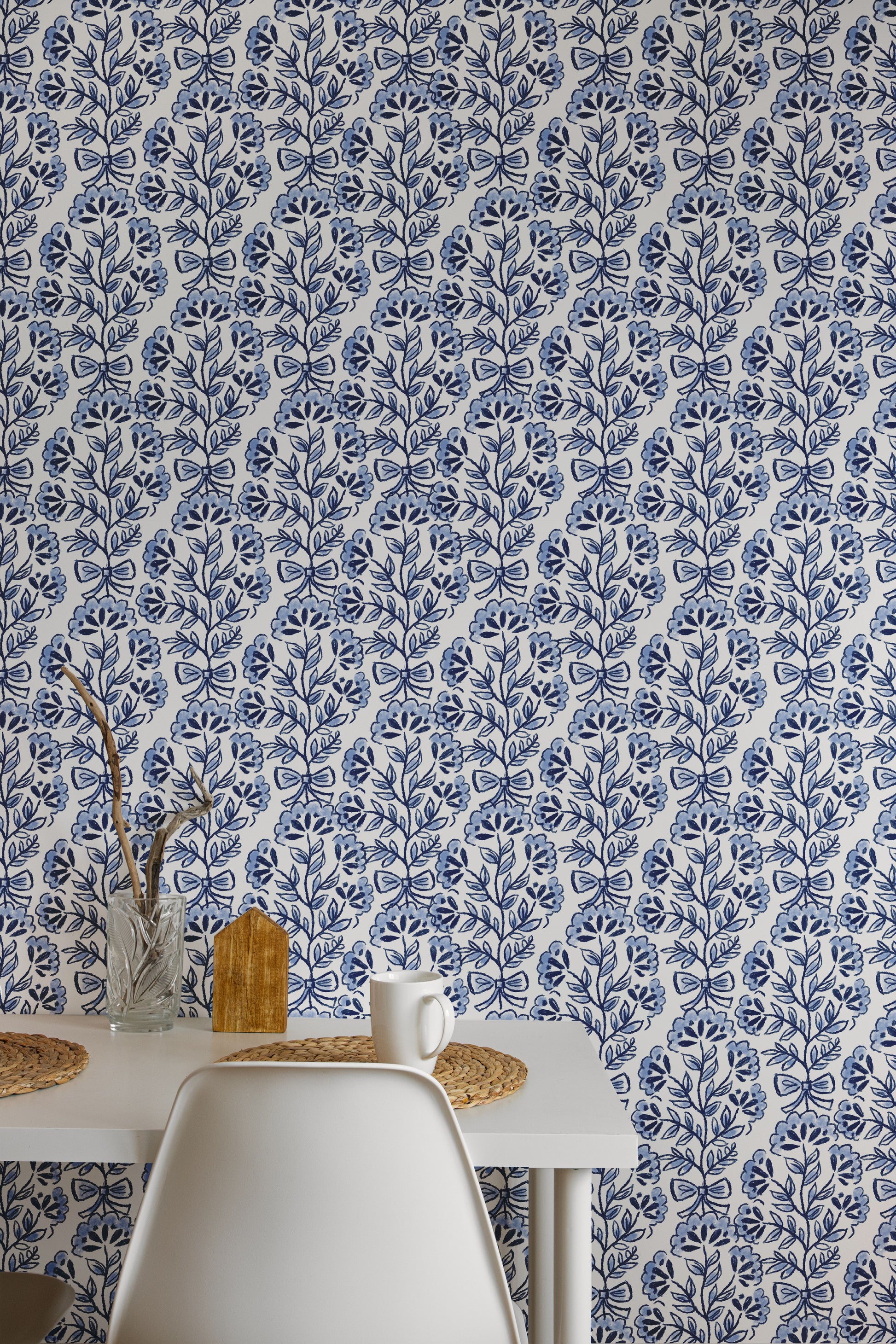 A table and chairs against a blue and white floral patterned wall.