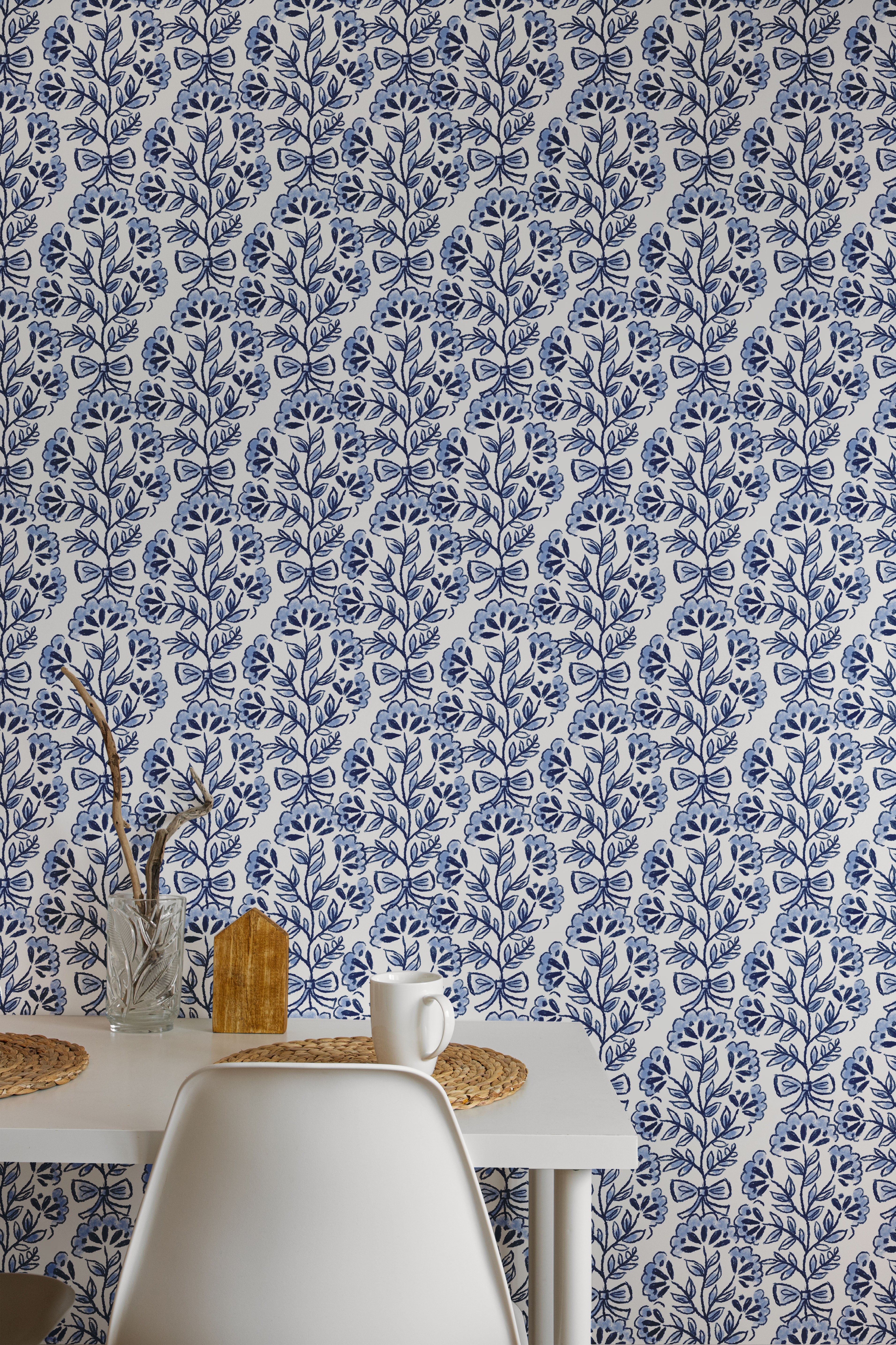 A table and chairs against a blue and white floral patterned wall.