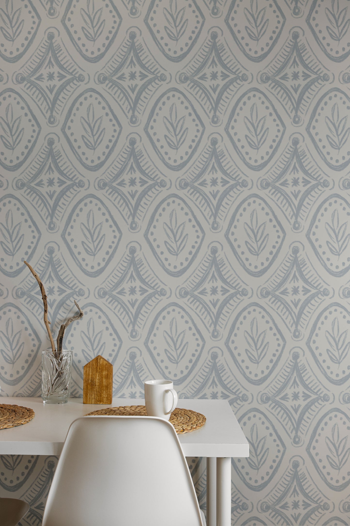 Dining area with a table against a wall featuring a geometric patterned wallpaper.