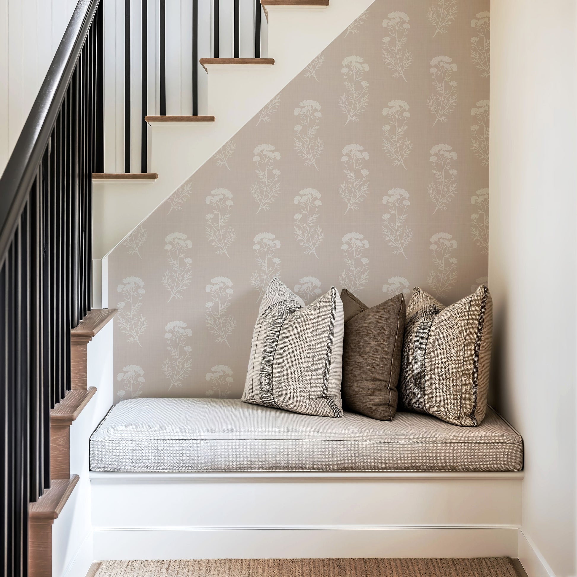 Stair landing with a cushioned bench and decorative pillows against a patterned wall.