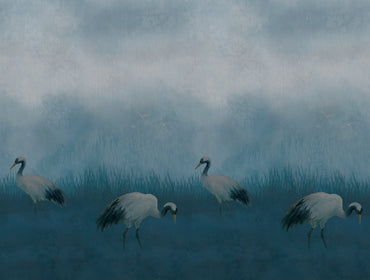 A misty blue-toned landscape artwork showing four white cranes walking through reeds under a cloudy sky.