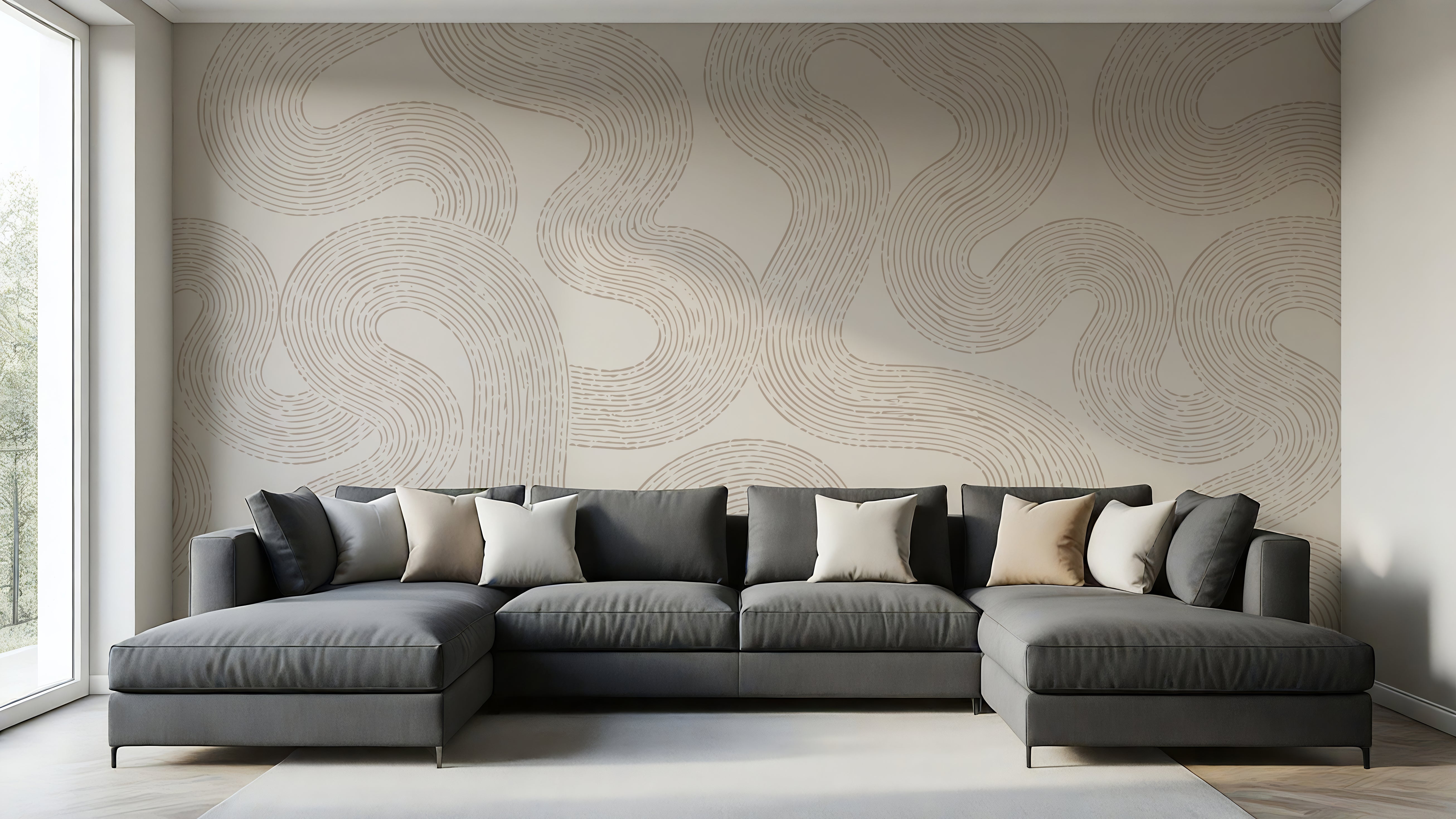 A modern L-shaped sectional sofa in dark gray with beige and white accent pillows, set against a wall with a large beige abstract wavy patterned wallpaper in a bright, contemporary living room.
