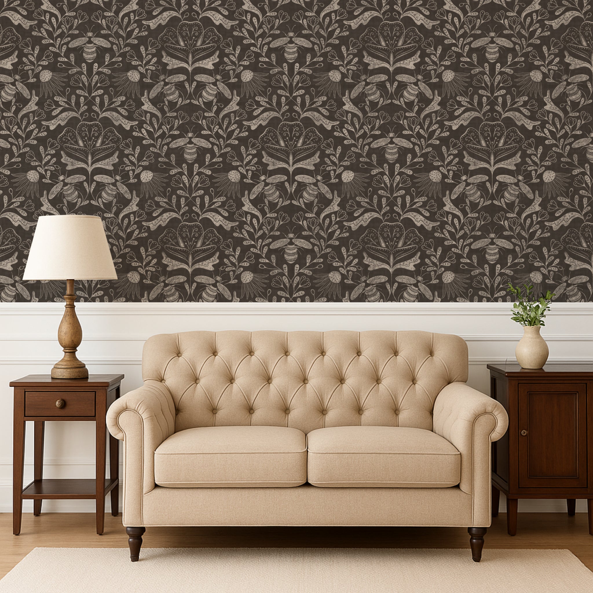 Beige tufted sofa in a room with patterned wallpaper and wooden furniture.