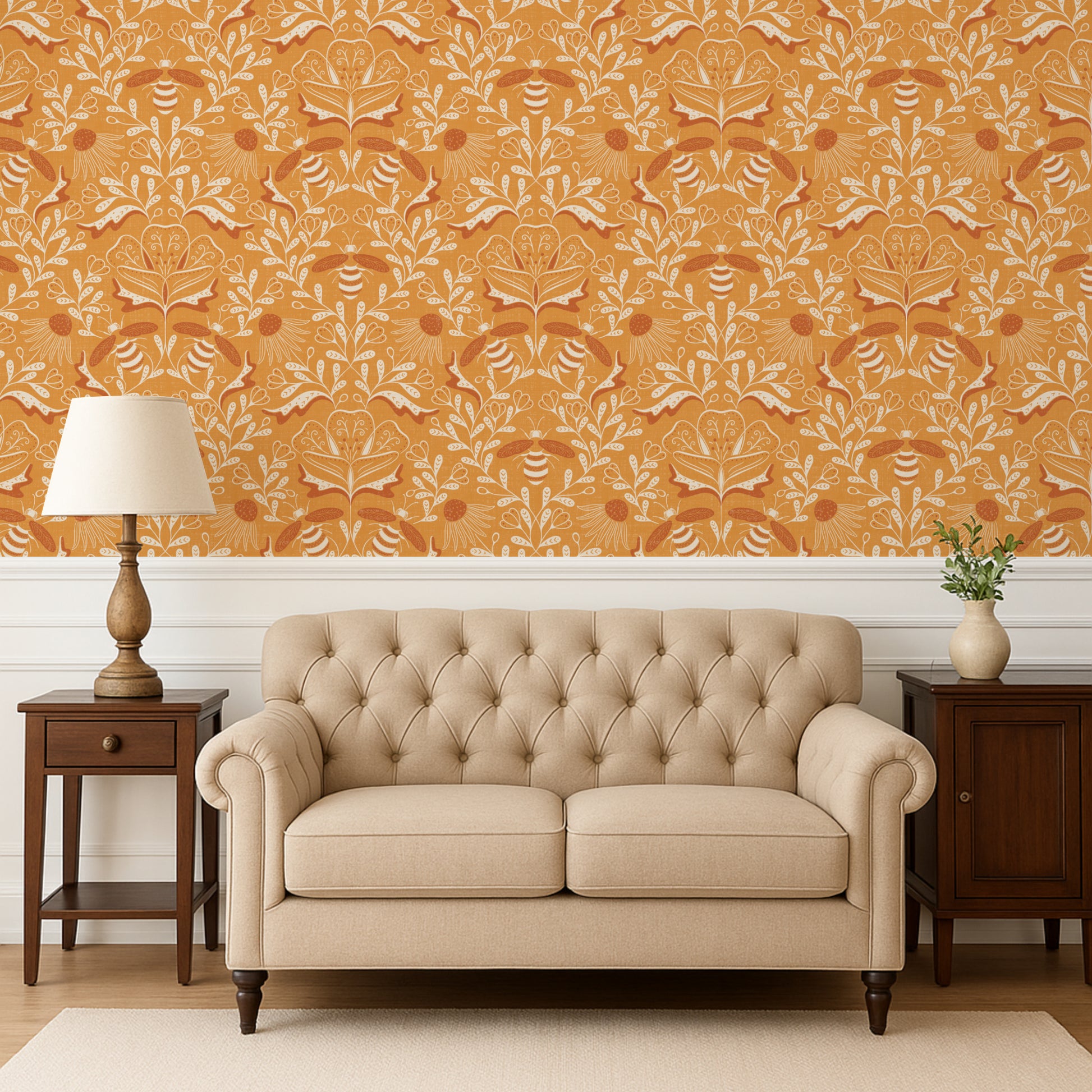 Beige tufted sofa in a room with orange patterned wallpaper, wooden side tables, and a lamp.