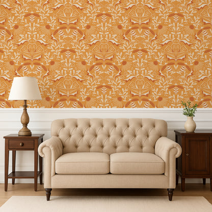 Beige tufted sofa in a room with orange patterned wallpaper, wooden side tables, and a lamp.