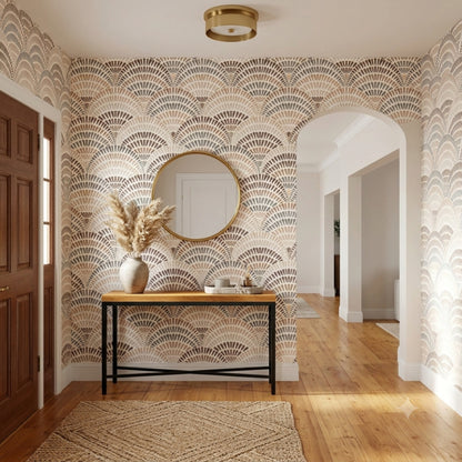 A styled entryway featuring a wall covered in a beige, brown, and gray scallop fan pattern wallpaper. A light wood console table with a black metal frame sits against the wall, decorated with a ceramic vase containing dried pampas grass.