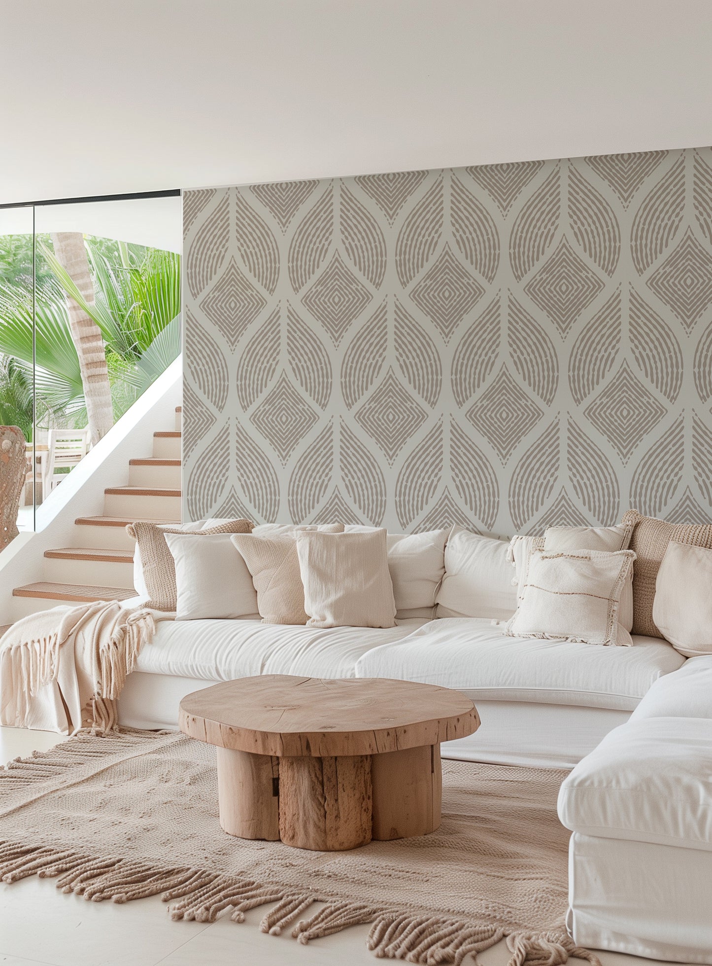 A modern living room featuring a large white sectional sofa with cream pillows, a round natural wood coffee table, and a prominent patterned wallpaper wall in warm beige and gray tones.