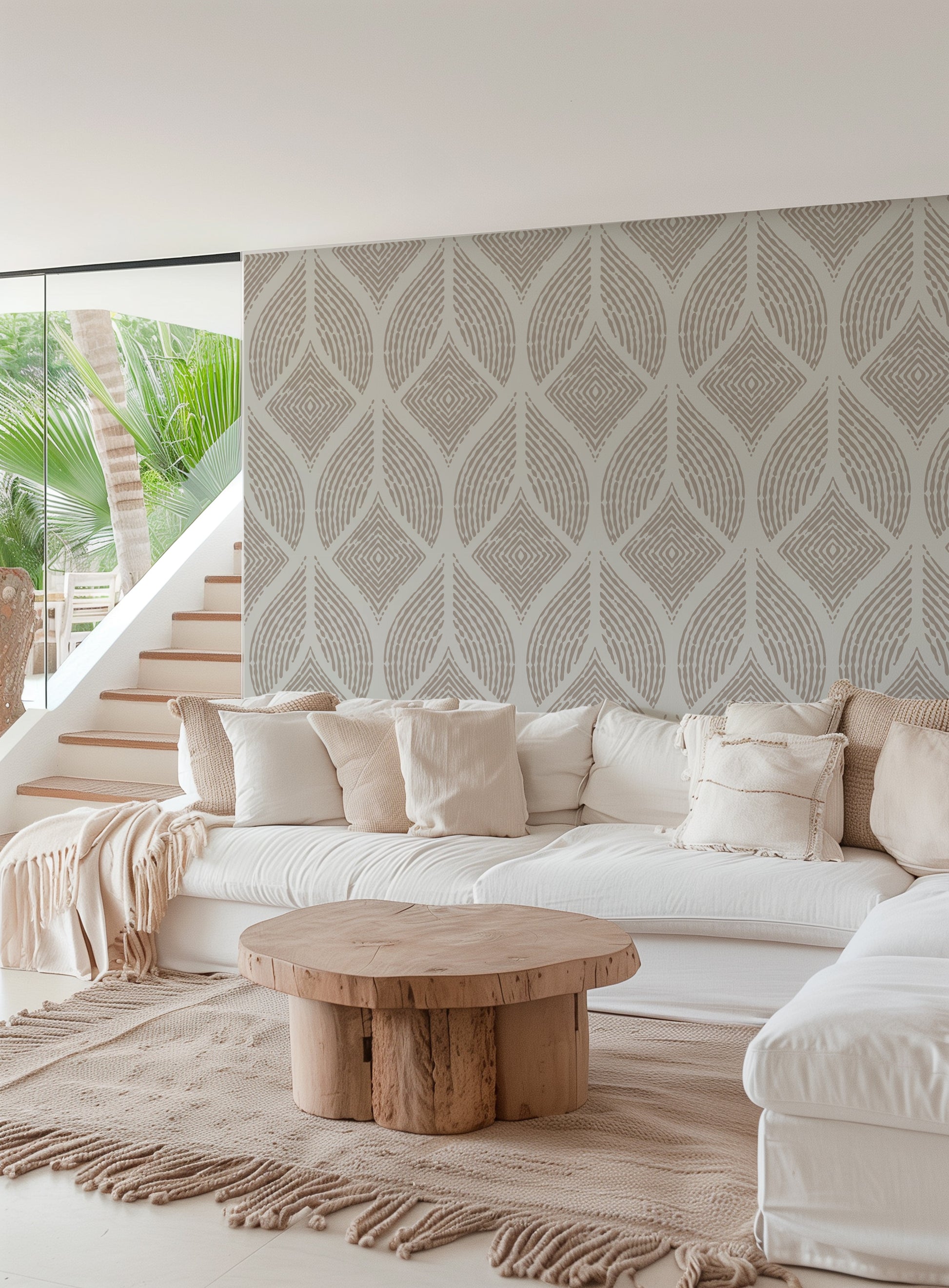 A modern living room featuring a large white sectional sofa with cream pillows, a round natural wood coffee table, and a prominent patterned wallpaper wall in warm beige and gray tones.