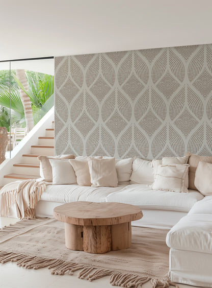 A modern living room featuring a large white sectional sofa with cream pillows, a round natural wood coffee table, and a prominent patterned wallpaper wall in warm beige and gray tones.