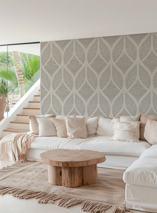 A modern living room featuring a large white sectional sofa with cream pillows, a round natural wood coffee table, and a prominent patterned wallpaper wall in warm beige and gray tones.